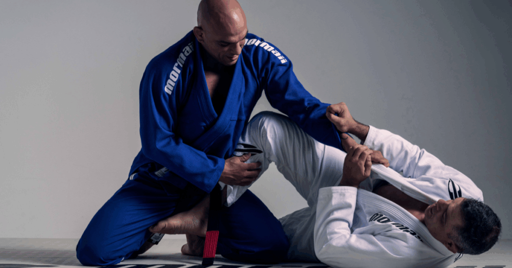 “Two athletes training Brazilian jiu-jitsu wearing Mormaii gis, one in blue and one in white, during a grappling position on the mat.